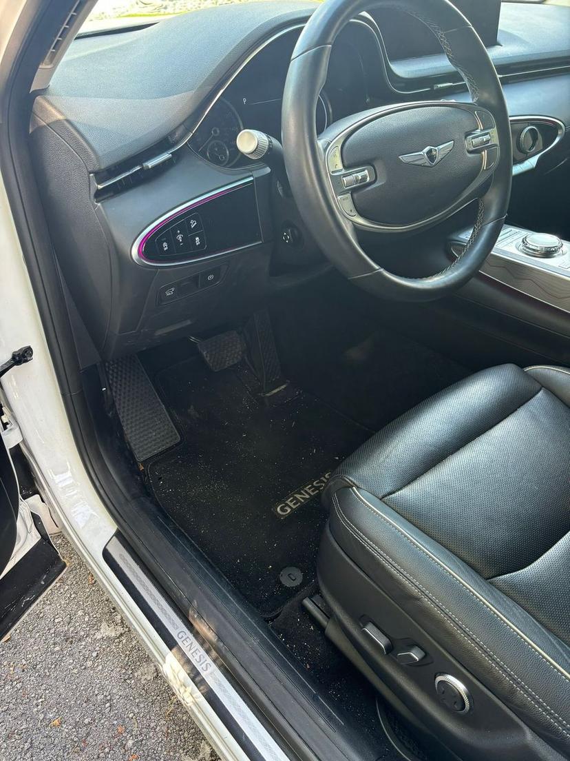 Genesis driver footwell with dirt and debris on the carpet before cleaning
