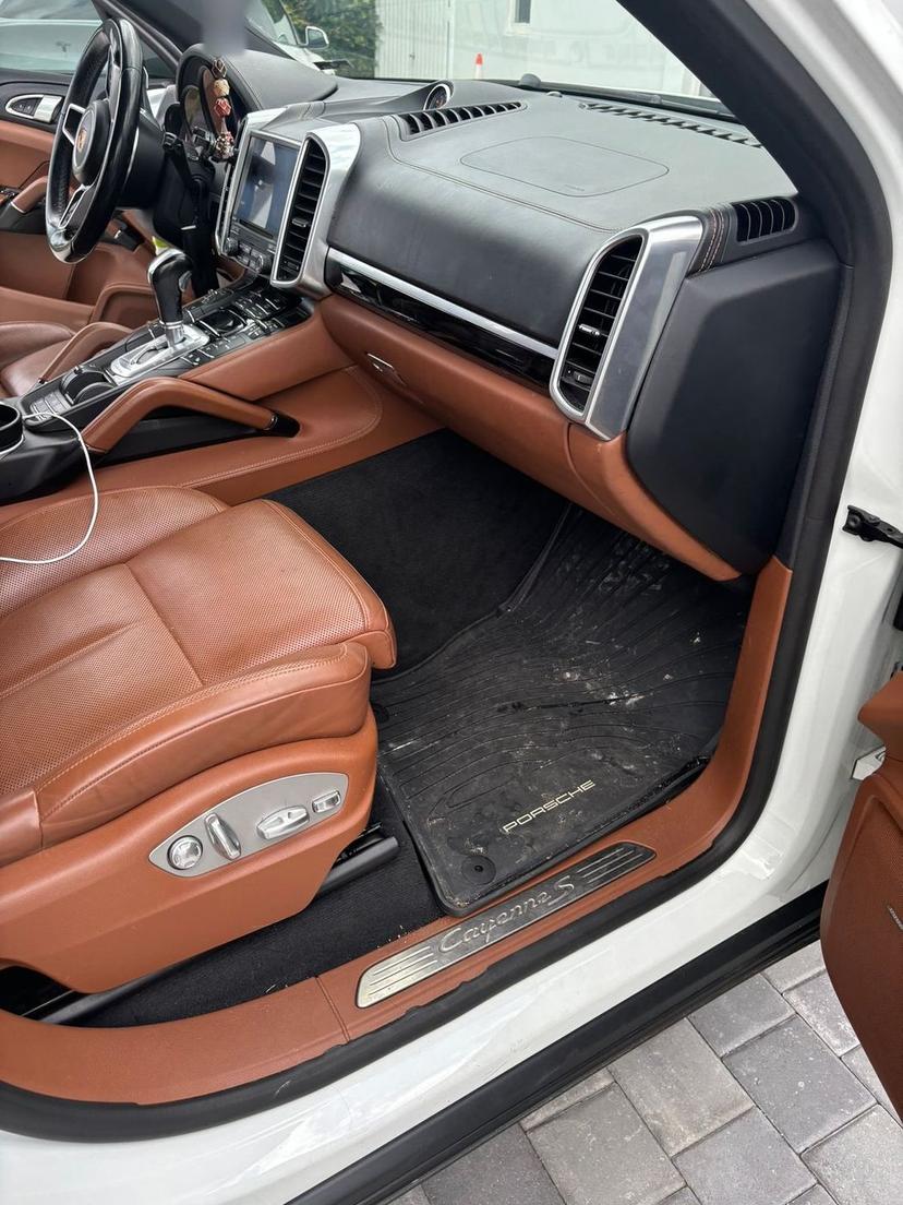 Porsche Cayenne footwell with a muddy rubber mat before cleaning